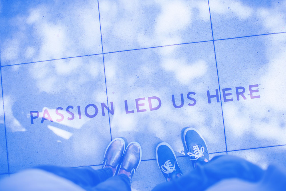 Passion led us here written on the sidewalk with 2 pairs of feet